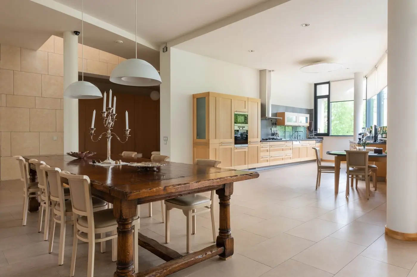 Bright dining room and kitchen with stone wall and wood table